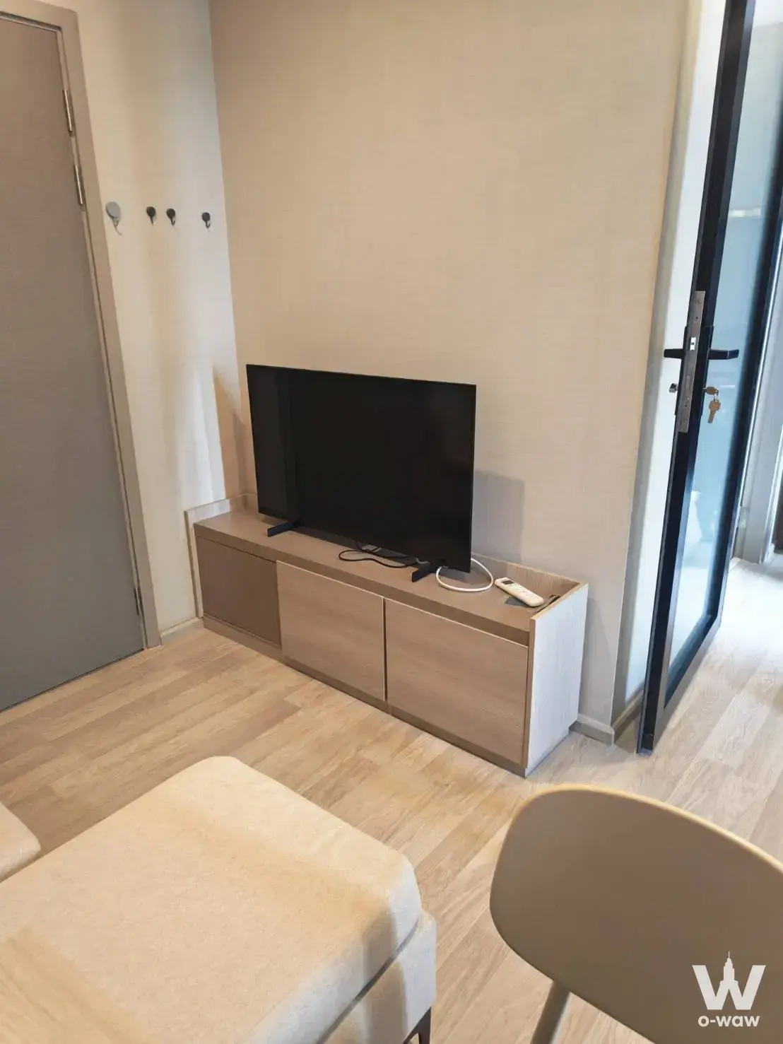 Living area with light wood flooring and media console in a 1-bed condo for sale at IDEO Mobi Sukhumvit