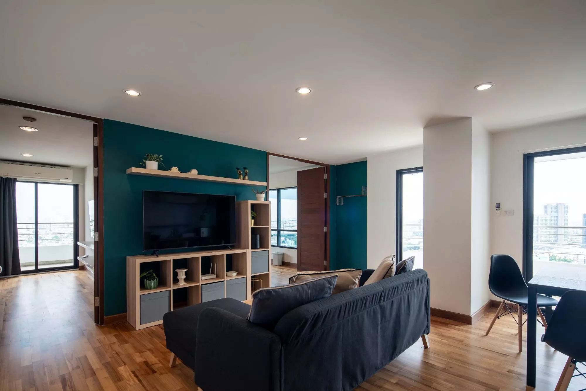 Modern living room with teal feature wall and city views in 2-bed condo for rent at Sarin Place