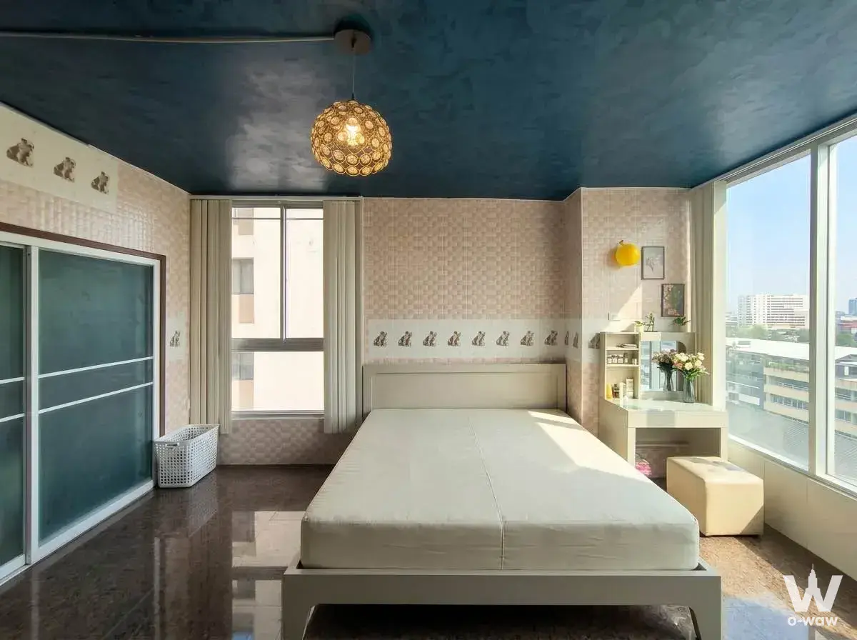 Bright bedroom in La Maison 24 condo with dark blue ceiling, beige wallpaper, and city views from large windows