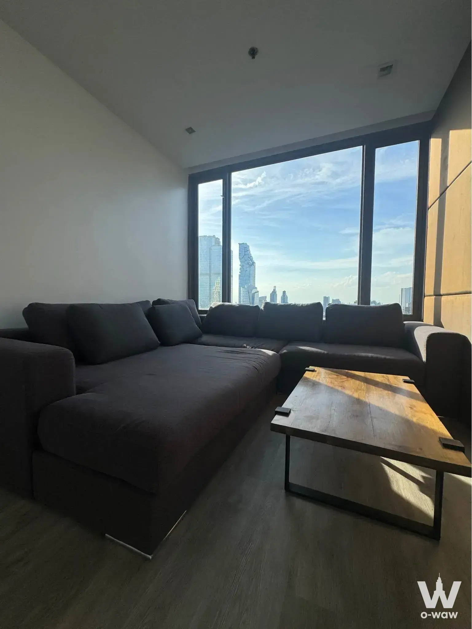 Modern living room with L-shaped sofa and floor-to-ceiling windows in 2-bed condo for rent at Nara 9 by Eastern Star
