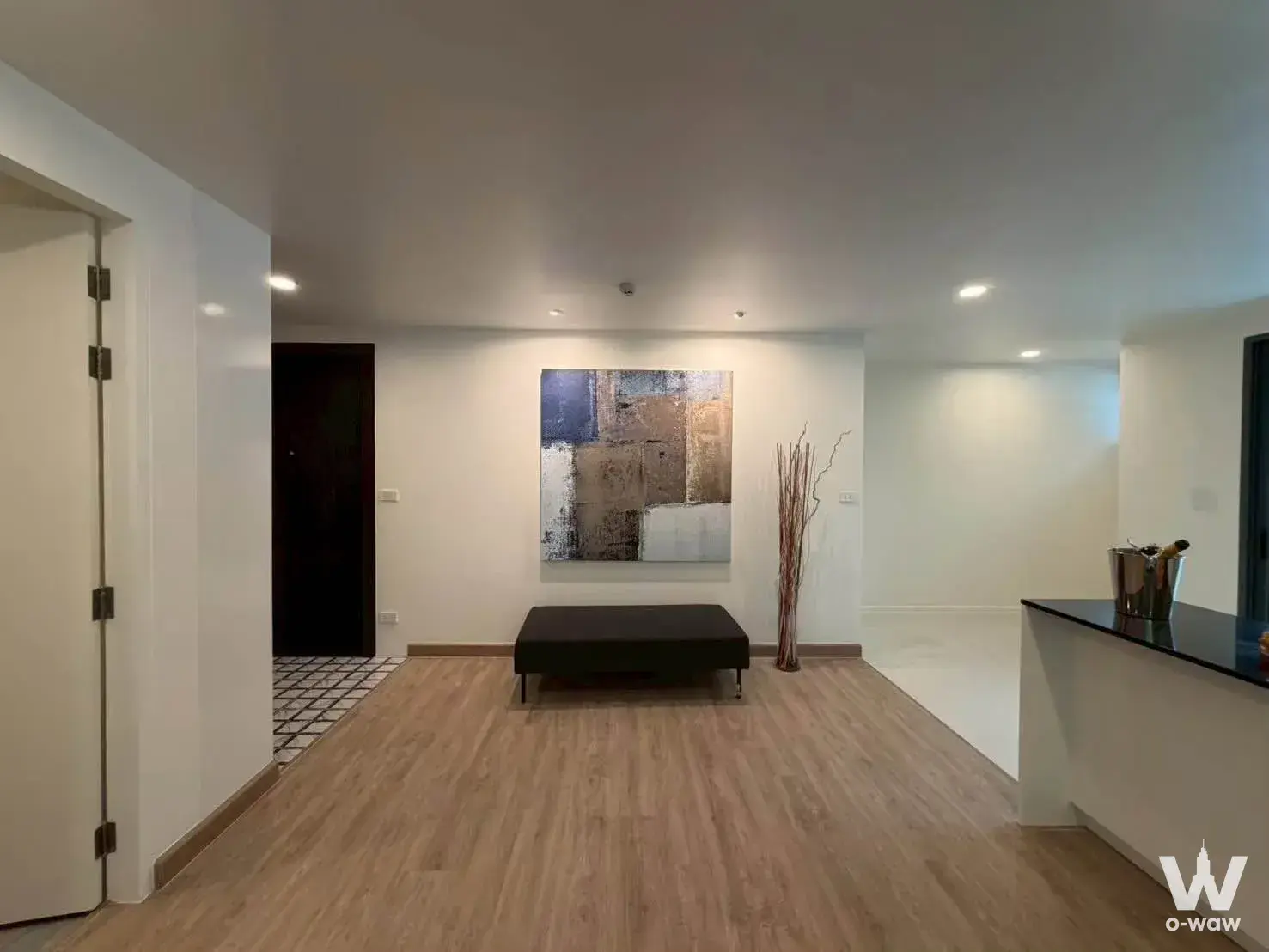 The entry area in a 2-bed Voque Sukumvit 31 condo for sale has an abstract canvas and a black bench