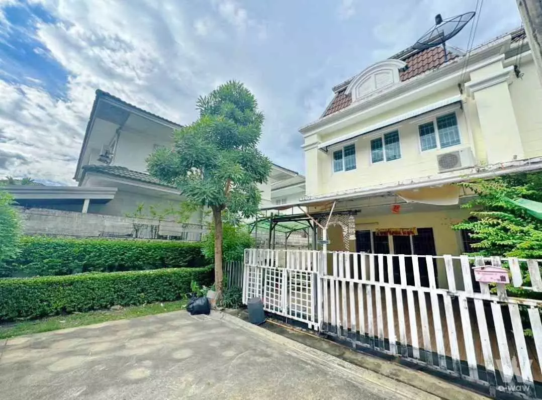 Cream stucco townhouse exterior with brown tiled roof and metal carport for rent in The Exclusive Townhome Bangkok