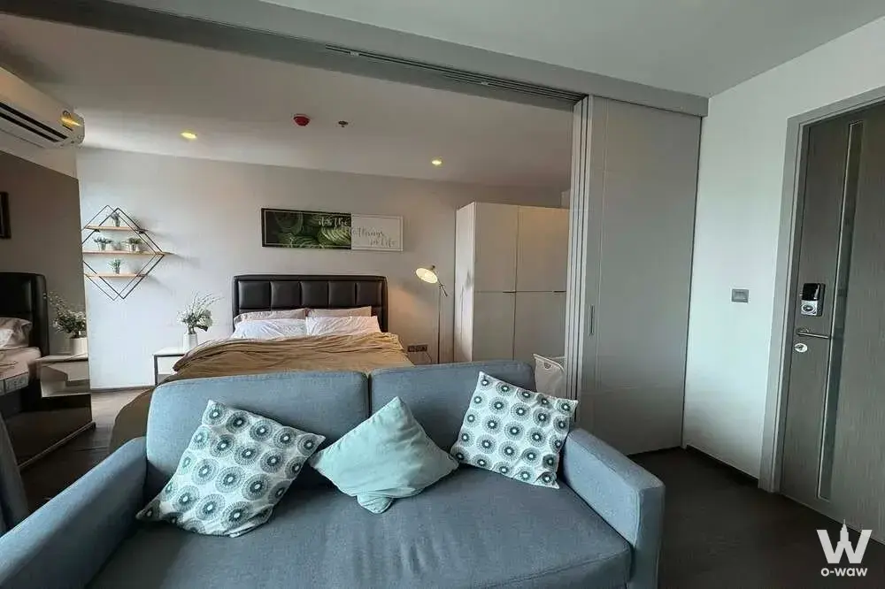 Modern 1-bed condo for sale in Ideo Q Siam-Ratchathewi with blue sofa, tufted headboard and wood-look floors