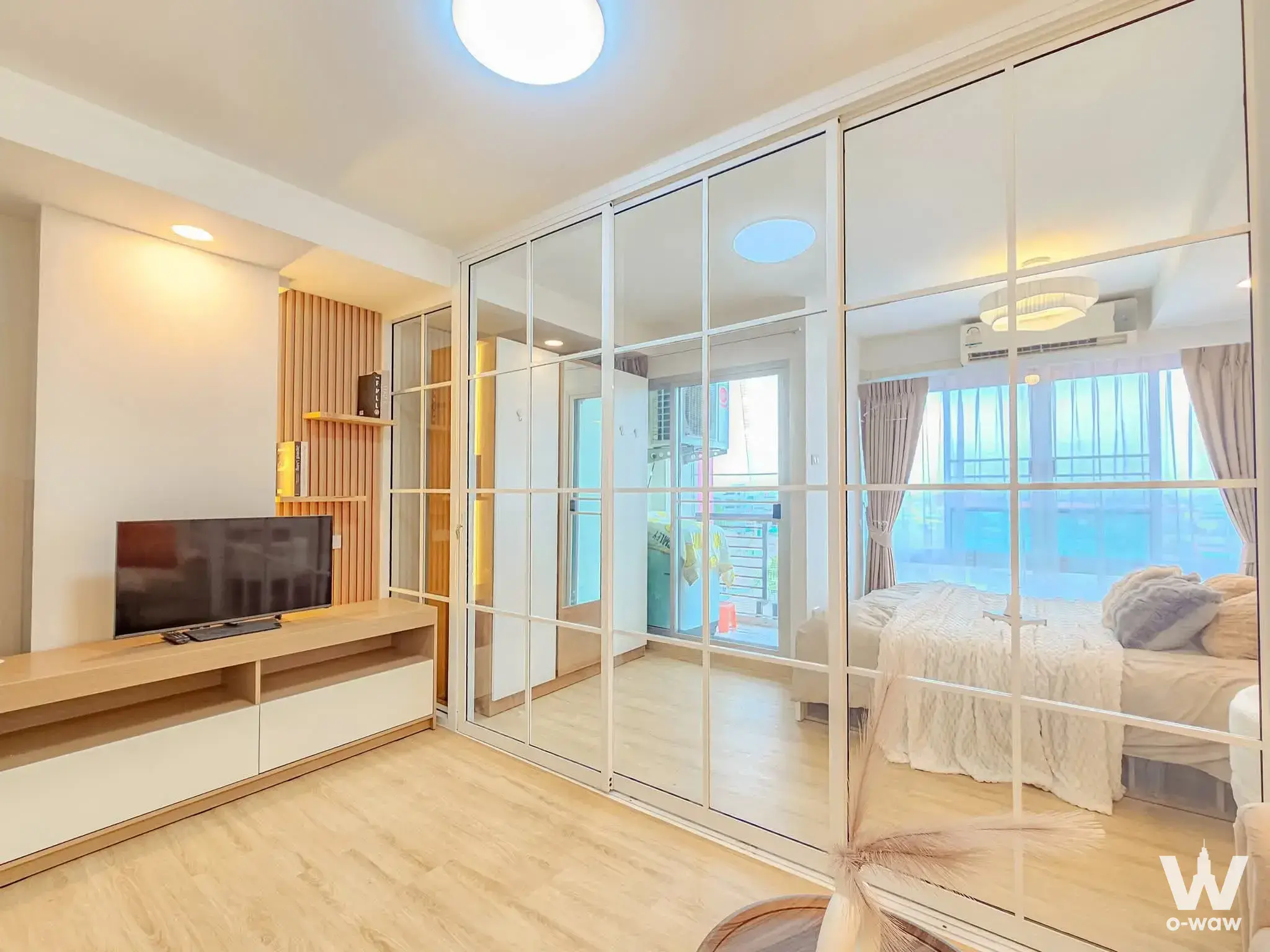 Modern living room and bedroom in 1-bed condo for sale at The Log 3 with wood slat accent wall and mirrored sliding doors