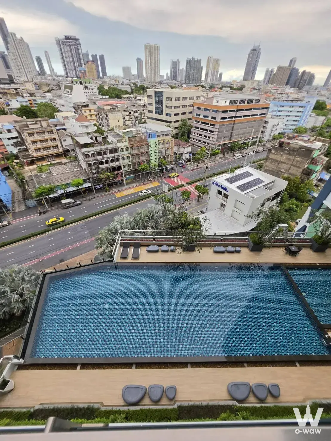 Rooftop infinity pool at 1-bed condo for sale in Supalai Premier Charoen Nakhon with lounge chairs and city views