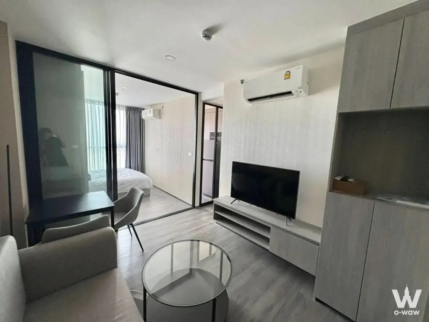 Living room with glass partition to bedroom in The Origin E22 Station 1-bed condo for rent