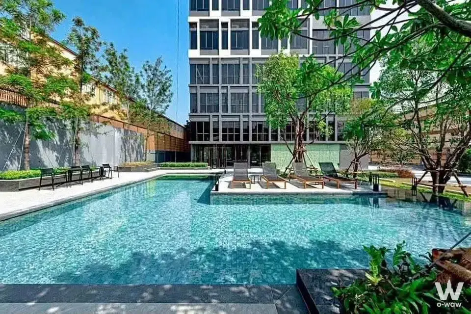 Turquoise pool with wooden loungers at Siamese Sukhumvit 87 condo