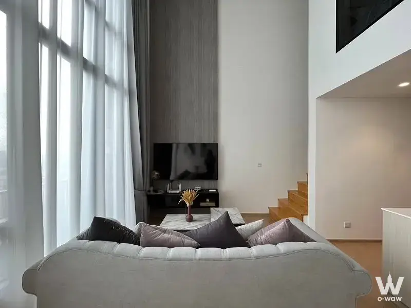 Modern living room in 2-bed MARU Ekkamai 2 condo with high ceilings, light wood floors, and large windows