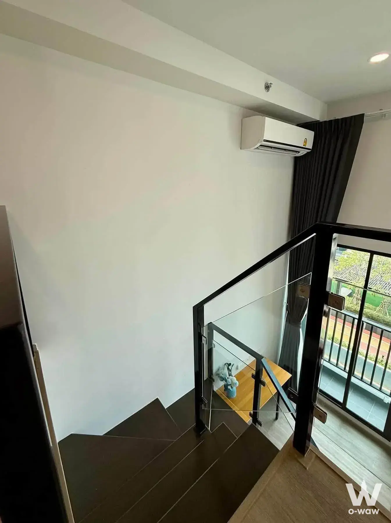Duplex stairwell landing with glass railing, wood flooring, and balcony access