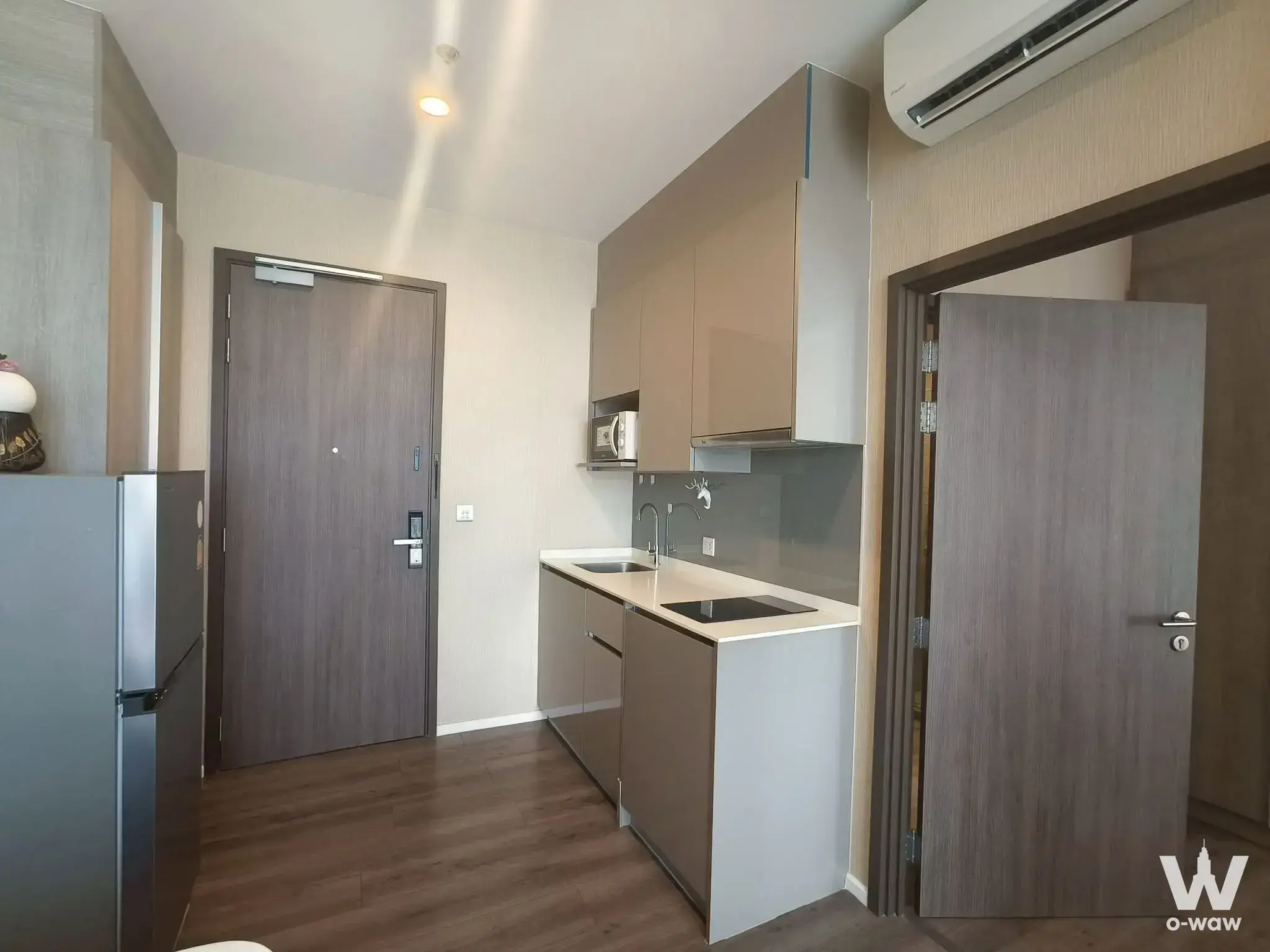 Modern 1-bed rent at Whizdom Essence Sukhumvit with open kitchen, taupe cabinets, and dark wood floors