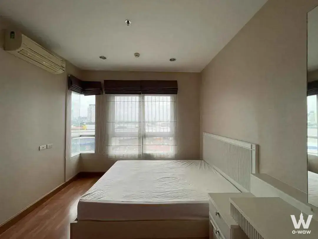 Bright 1-bed condo bedroom in Ivy River with wood floors, white bed, and city views through sheer curtains