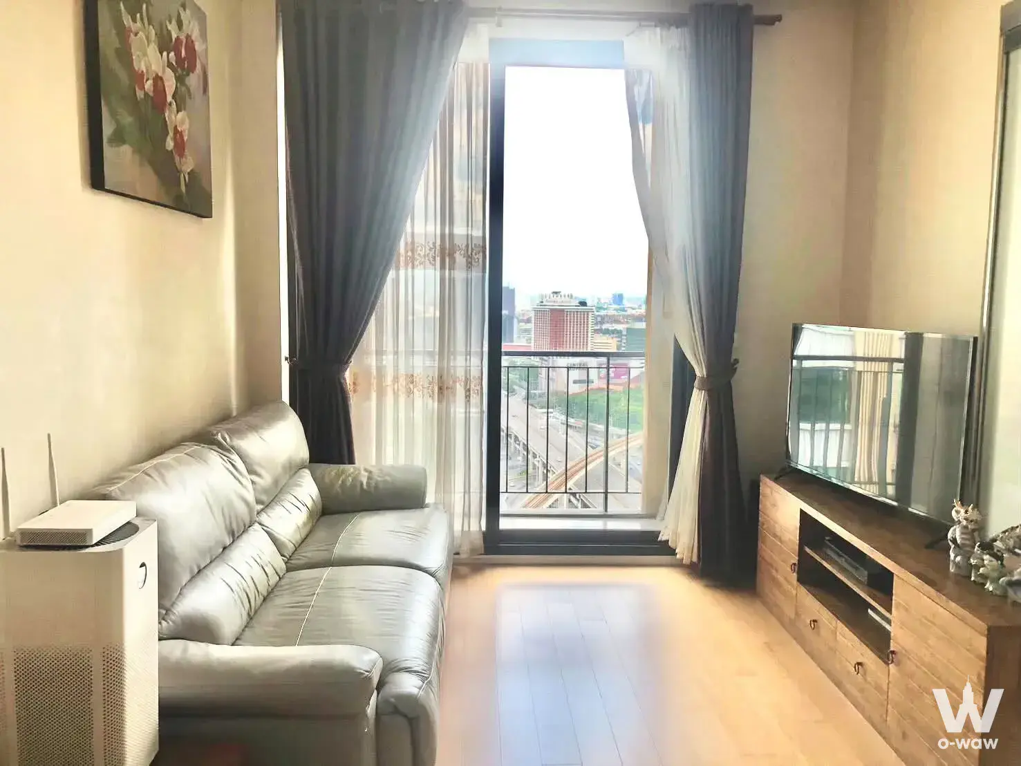 Living room with grey sofa and city view in Equinox Phahol-Vibha 1-bed condo for sale