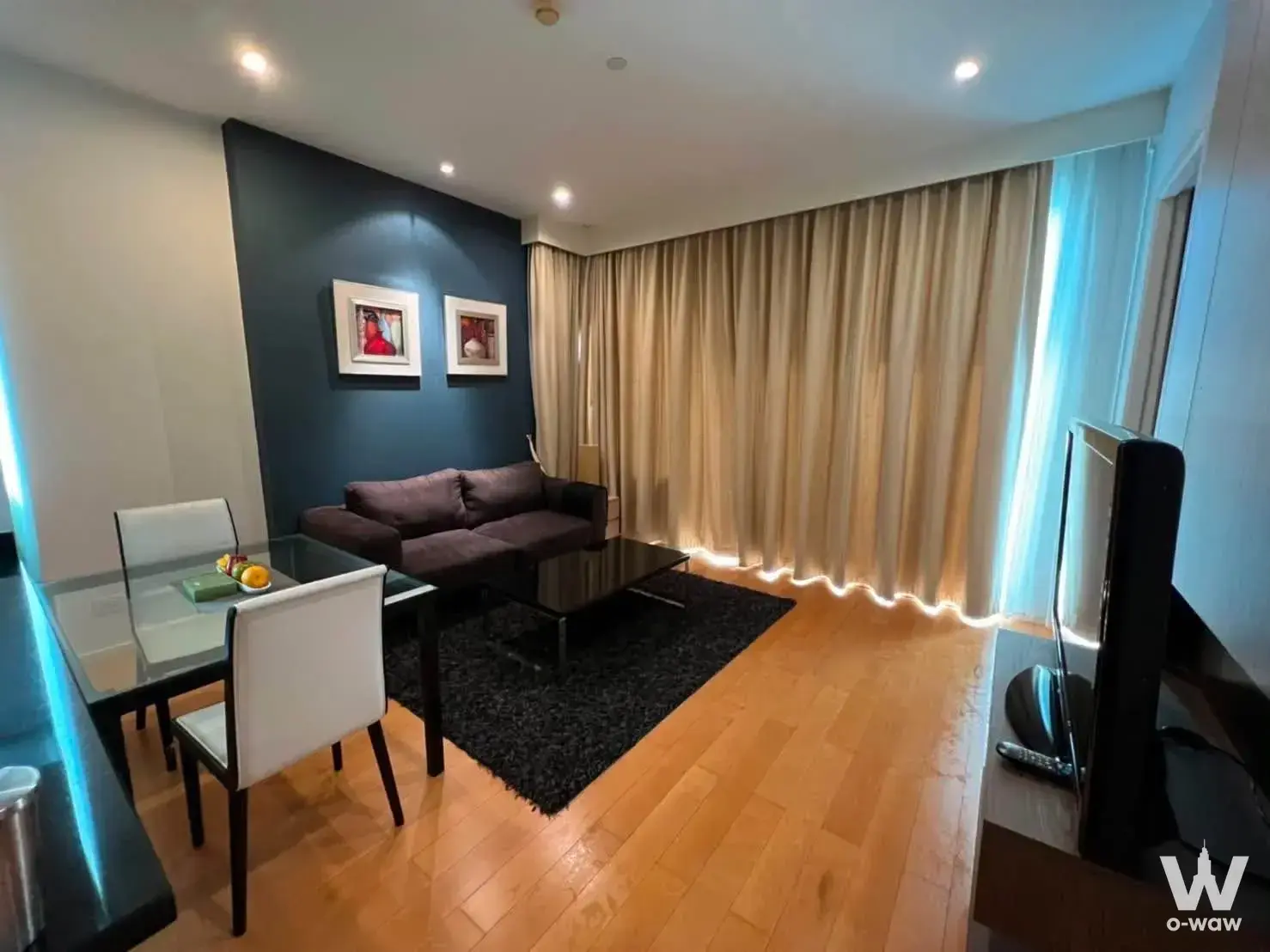 Living room featuring a dark navy accent wall and glass dining table in Wind Ratchayothin Condominium