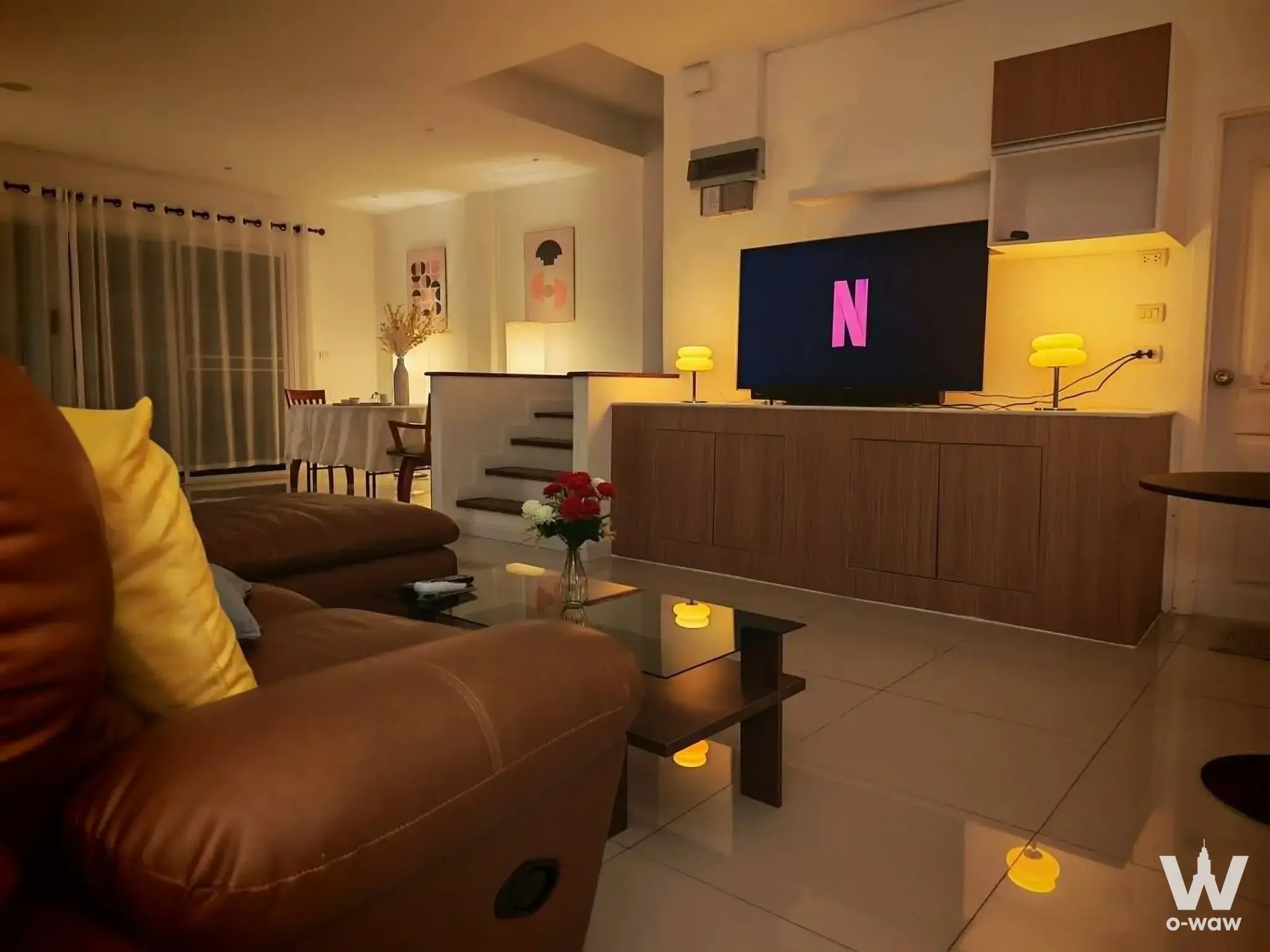 Modern living room in 6-bed Sathorn condo with leather sofa, yellow accents and floor-to-ceiling windows