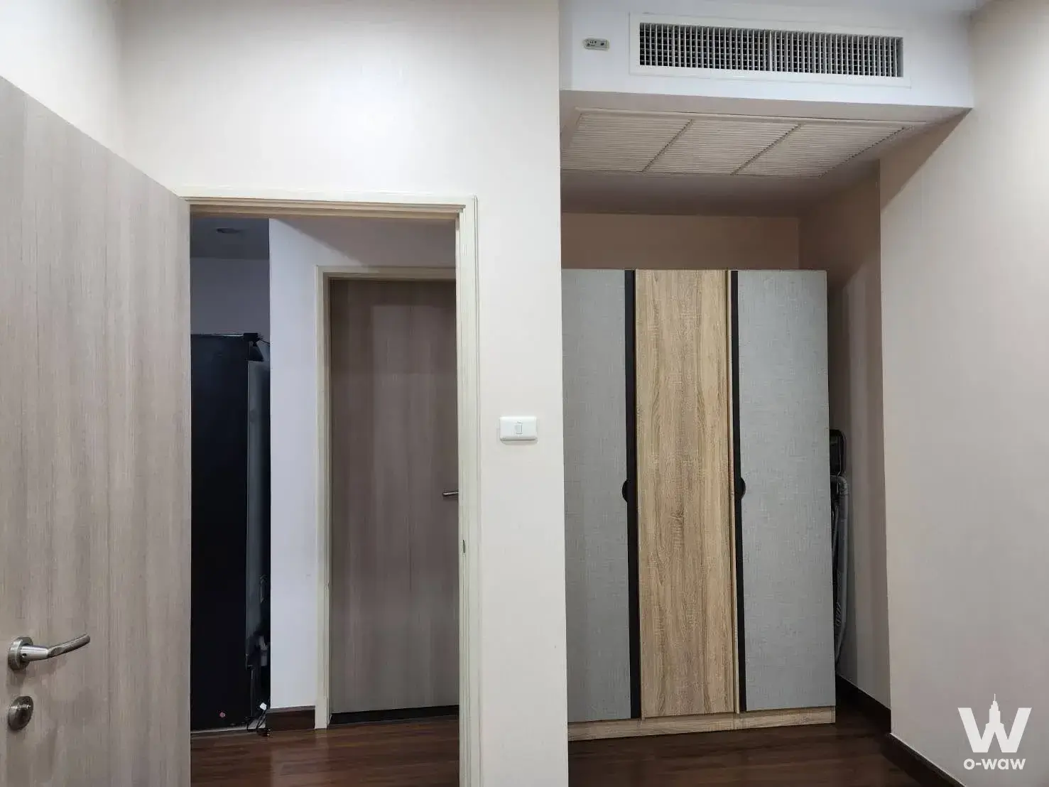 Modern bedroom hallway with dark wood flooring and built-in sliding wardrobe in 1-bed condo for rent at Supalai Lite