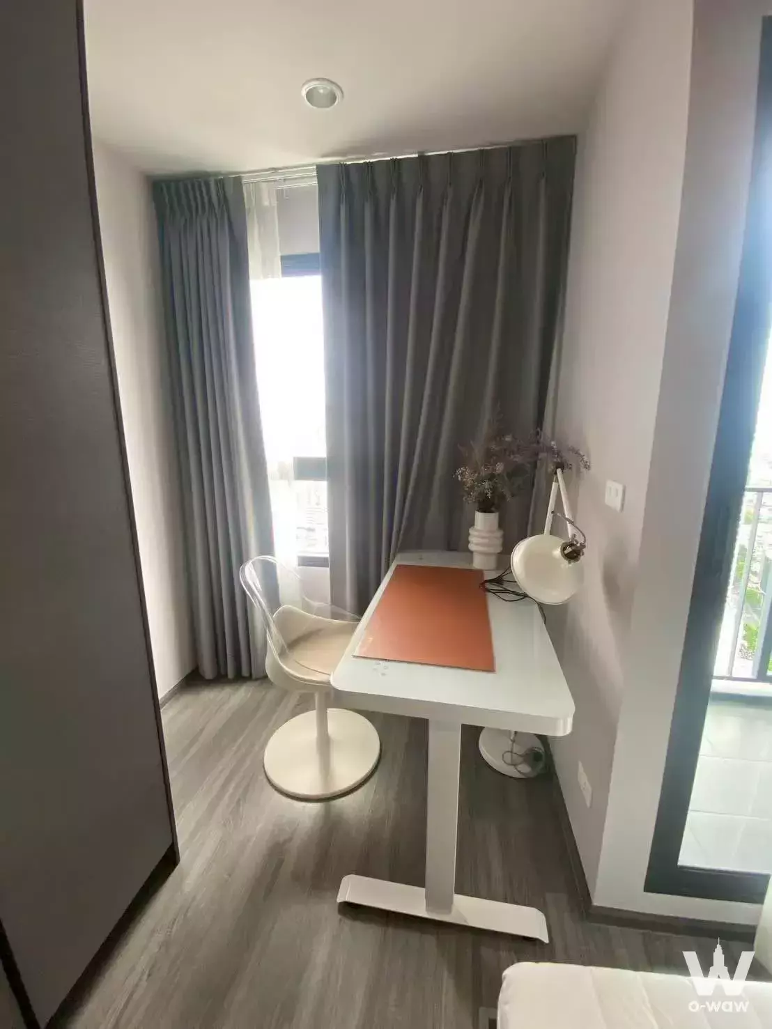 Modern home office nook in 1-bed IDEO Chula-Sam Yan condo with white desk, grey curtains, and balcony view