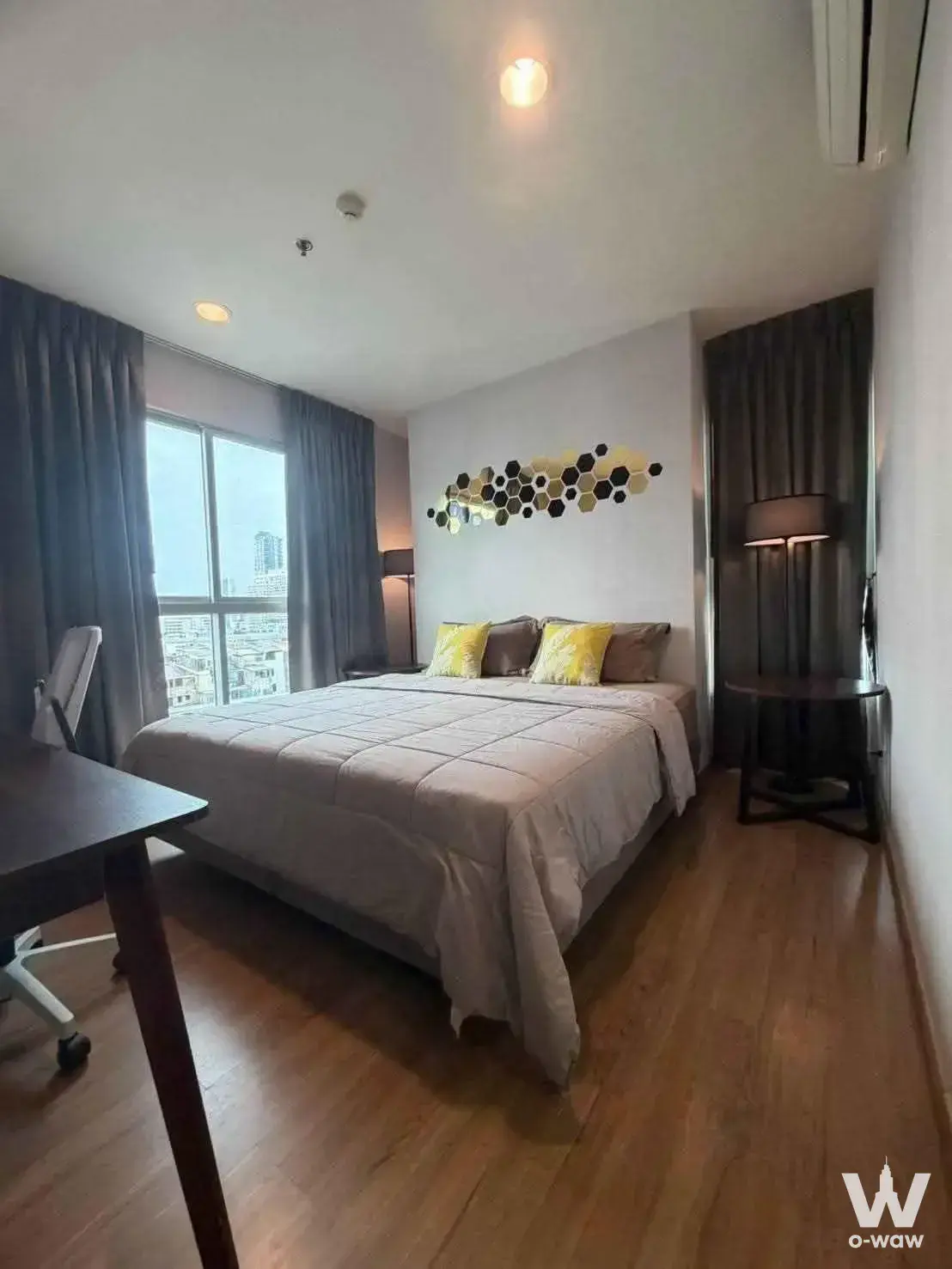 Modern bedroom in a 2-bed unit at Fuse Chan Sathorn with a queen bed, hexagonal wall art, and a city skyline view through