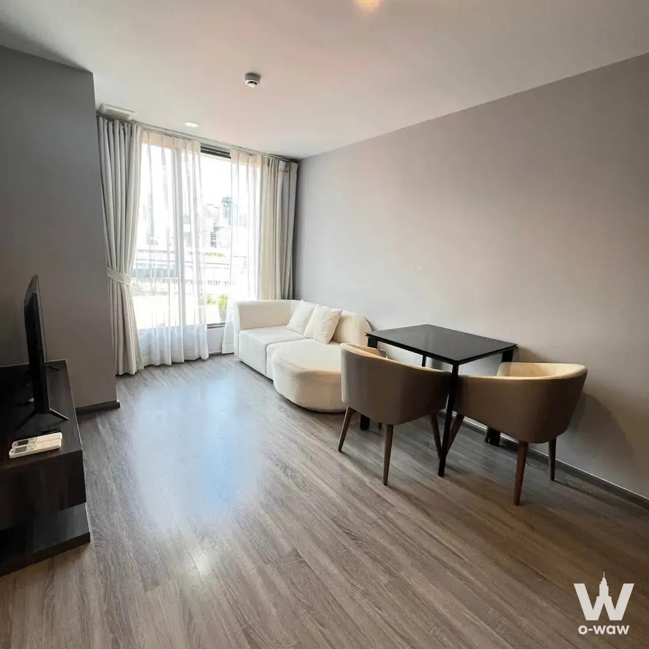 Living room with curved sofa and balcony access in an Ideo Mobi Sukhumvit 40 condo