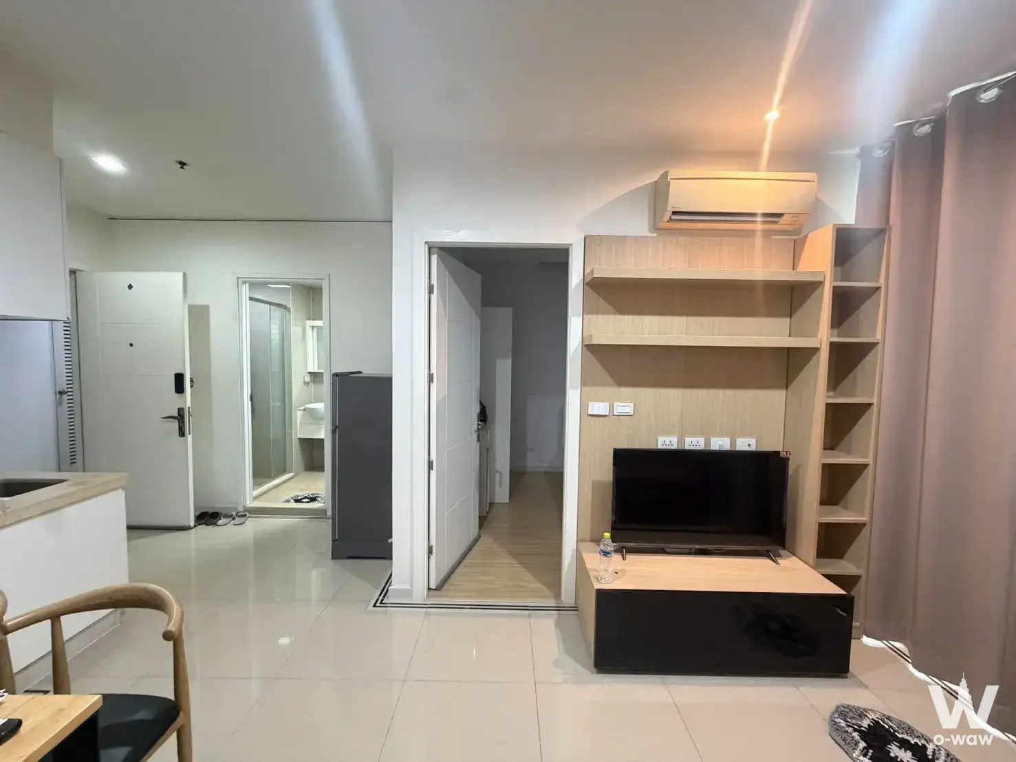 1-bed for rent in TC Green Rama 9 featuring open-plan living with oak entertainment unit and kitchenette