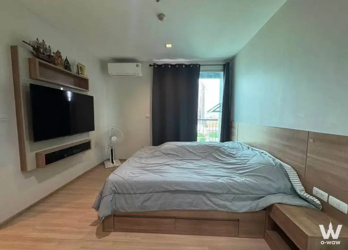 Cozy bedroom in RHYTHM Phahon-Ari condo with wood-paneled headboard and built-in TV niche