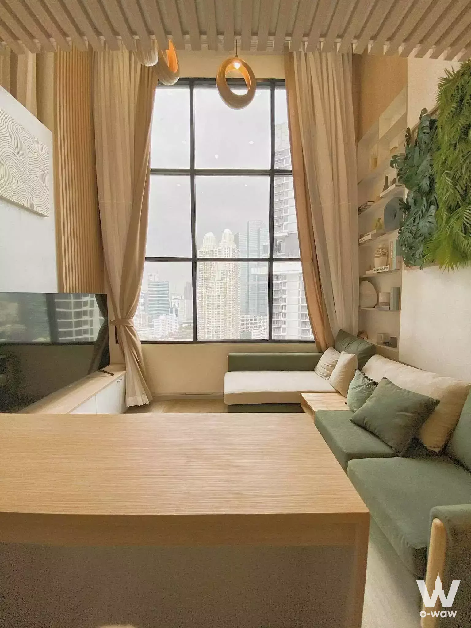 Sage green sofa and city views in KnightsBridge Prime Sathon 2-bed condo living room