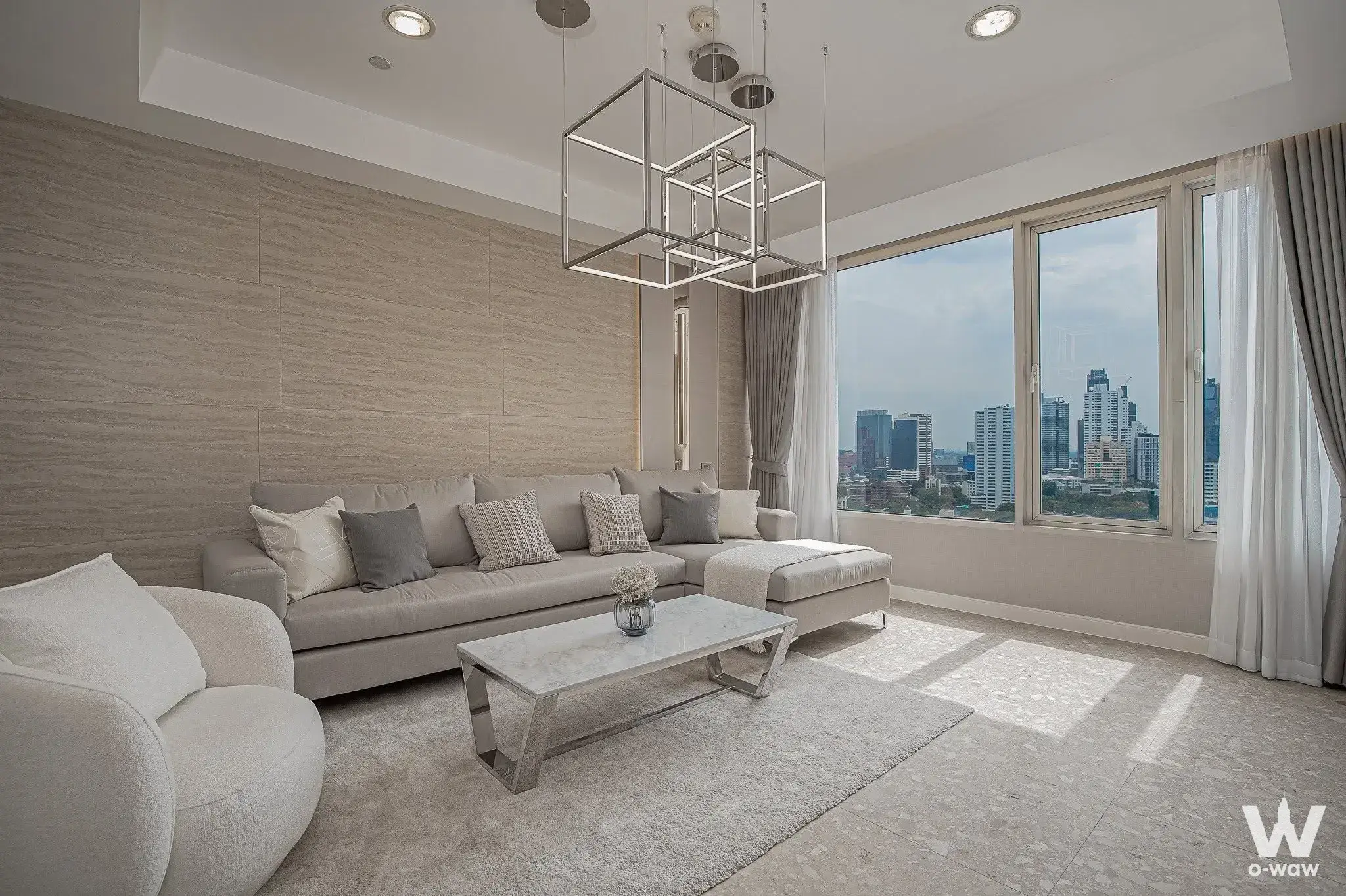 Living room in Hampton Thonglor 10 condo showcasing a grey sectional sofa, marble coffee table, and panoramic city views
