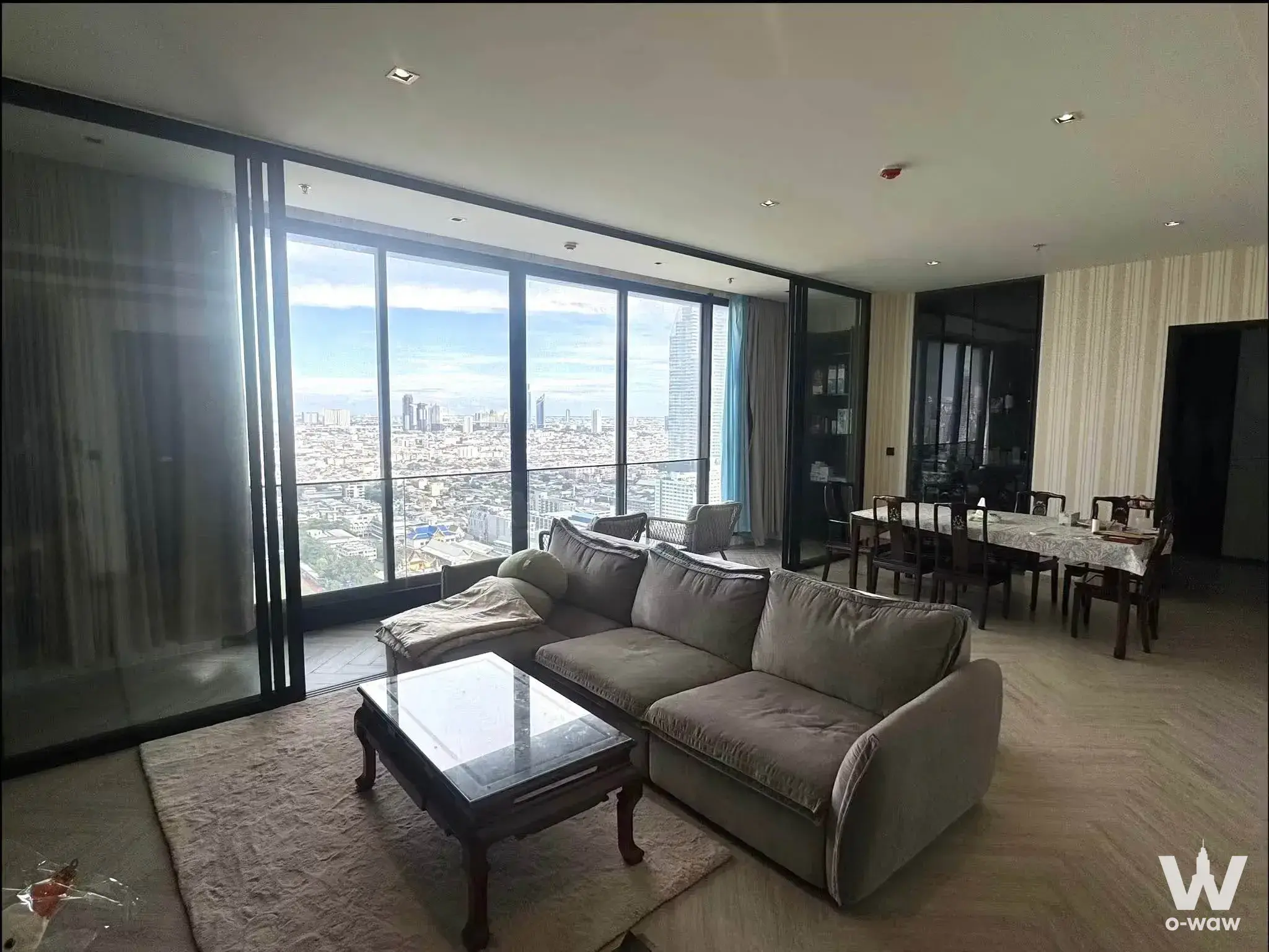 Grey sectional sofa and city skyline view in a 3-bed Chapter Charoennakhon condo