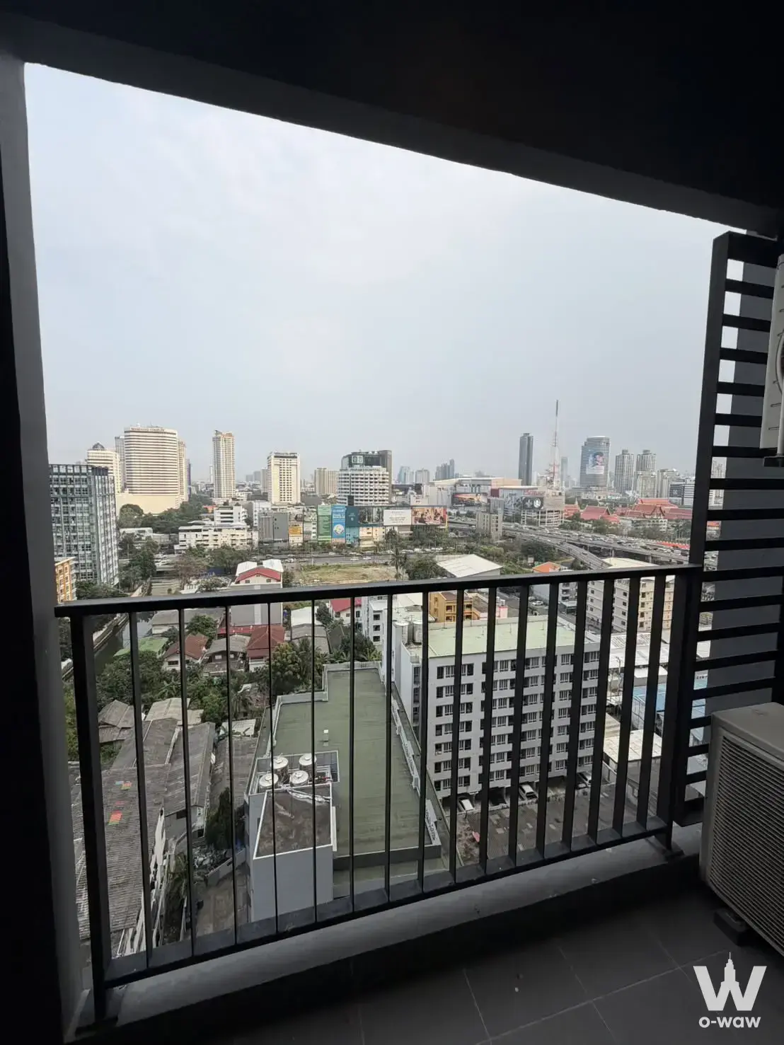 Unfurnished balcony at IDEO Rama 9 condo with dark tiles and expansive Bangkok cityscape view