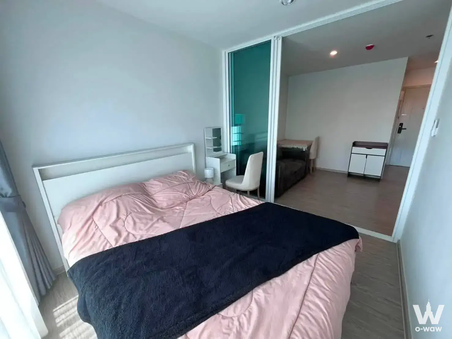 Minimalist bedroom in Regent Home Bangna featuring pink duvet, white vanity and sliding glass partition