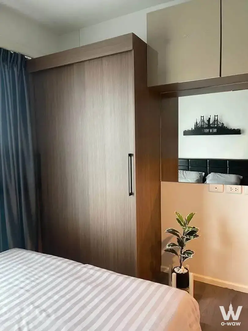 Cozy bedroom in The Stage Taopoon with a queen bed, dark wood wardrobe, and New York skyline wall decor