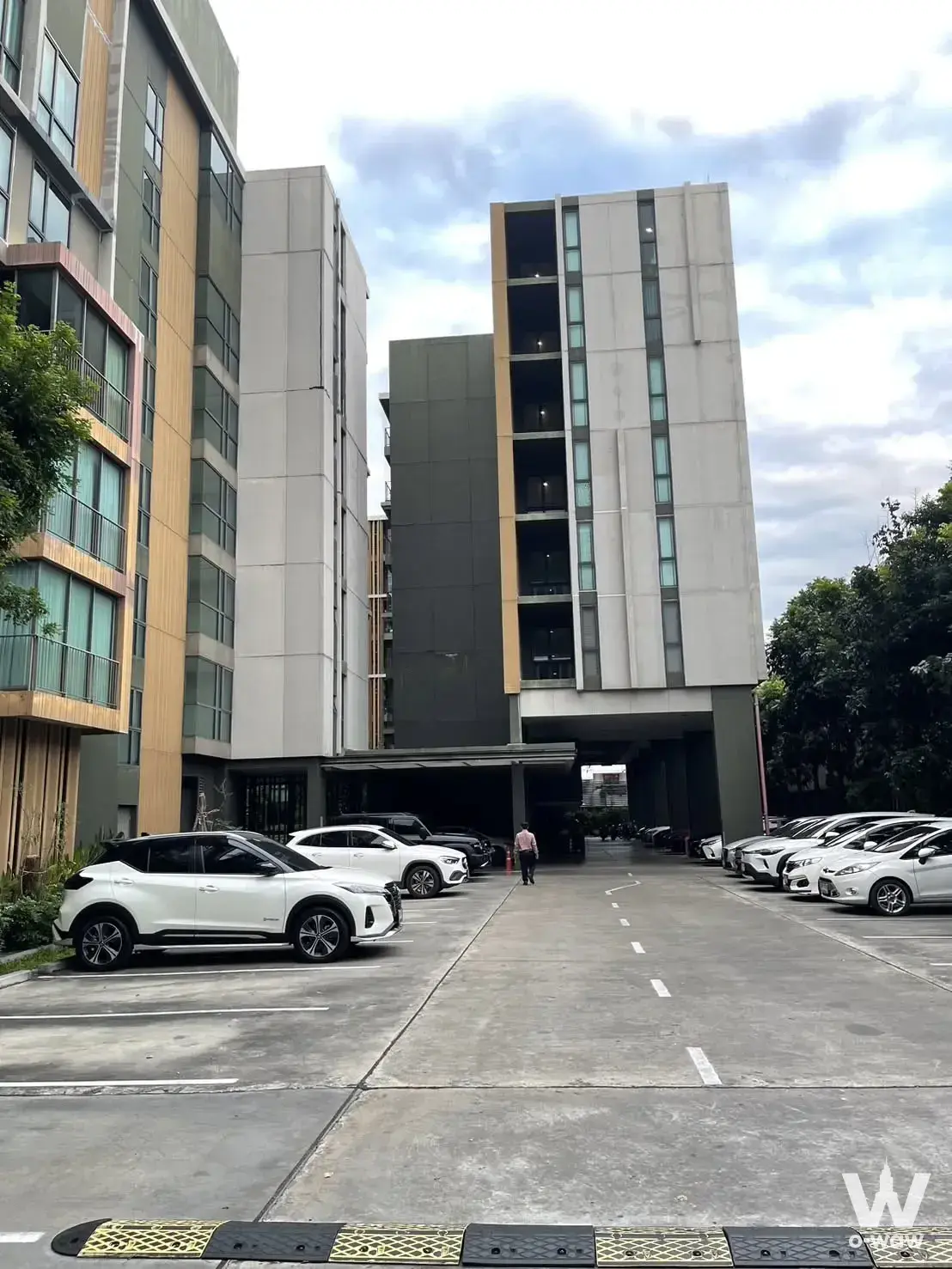 Modern condo exterior with wood-tone slats and parking area at CHAMBERS CHAAN Ladprao-Wanghin