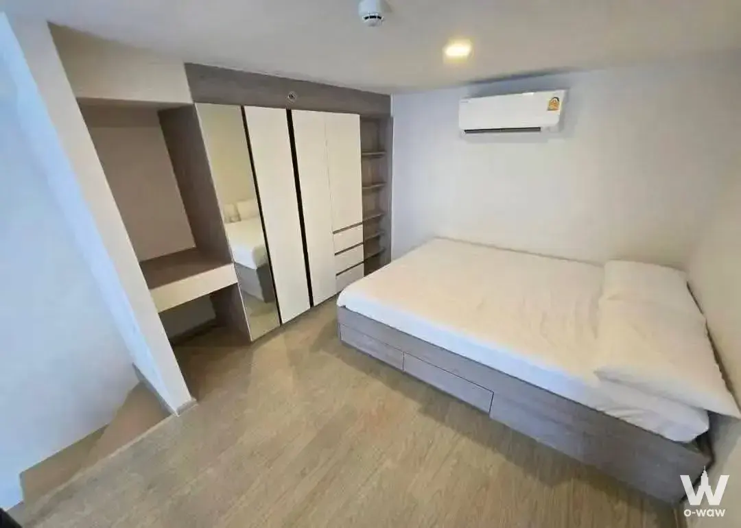 Queen bed and mirrored built-in wardrobe in a bright 1-bed condo bedroom for rent at Origin Plug & Play Ramkhamhaeng