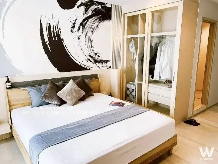 Modern bedroom in Life One Wireless 1-bed condo with light wood floors, queen bed, and abstract art