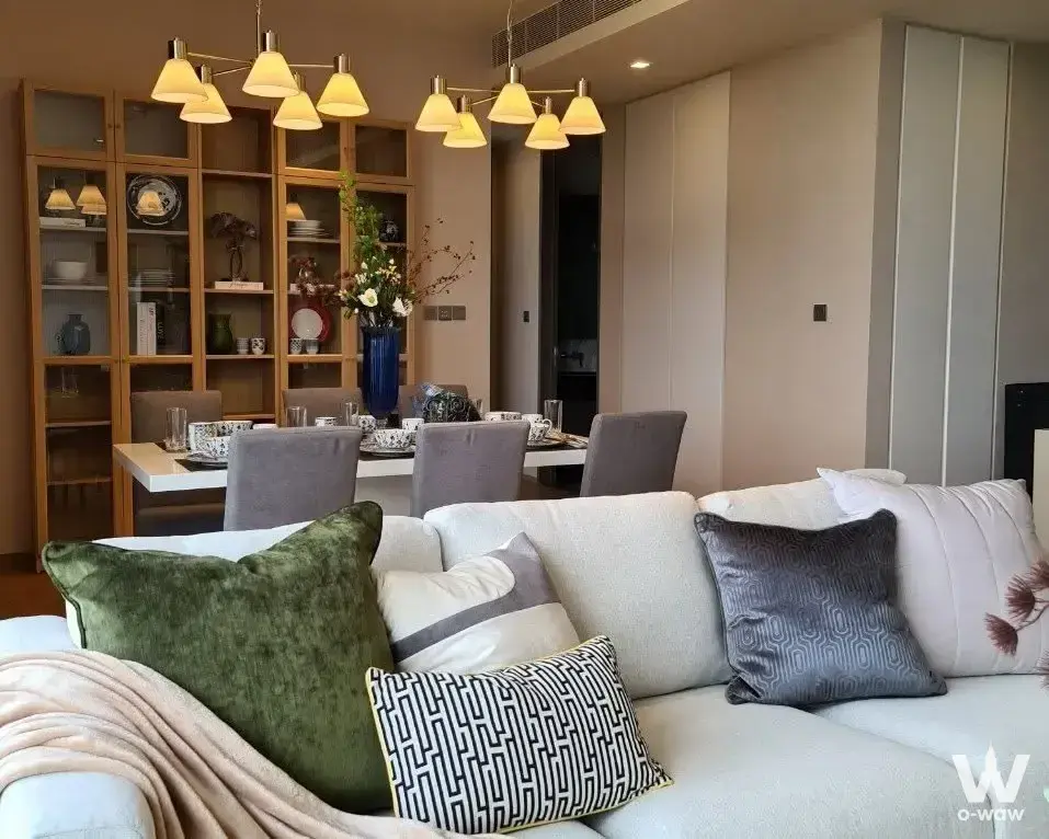 Furnished living and dining area with sectional sofa and chandeliers in 2-bed condo for rent in SALADAENG One