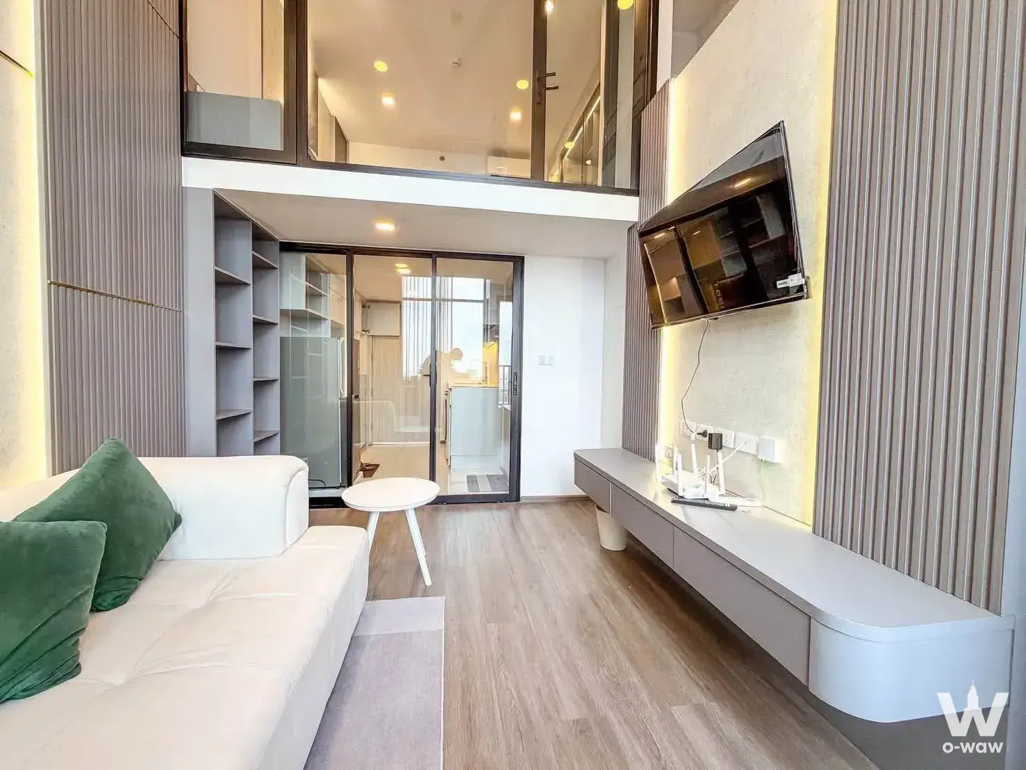 Modern loft living room in So Origin Kaset Interchange with mezzanine, white sofa, and fluted media wall