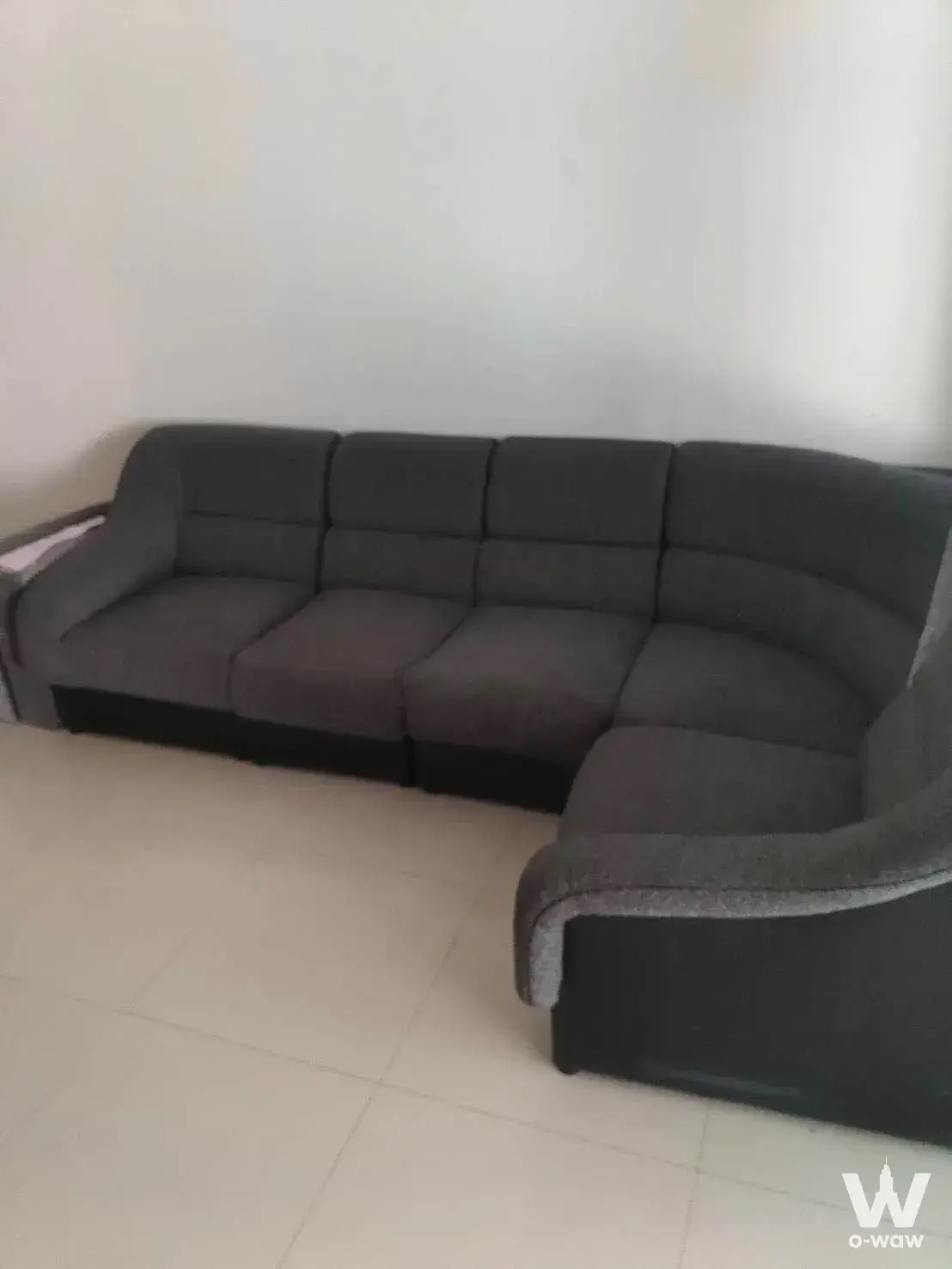 Spacious living room with grey L-shaped sectional sofa in 3-bed townhouse for rent at Patio Phatthanakan 38