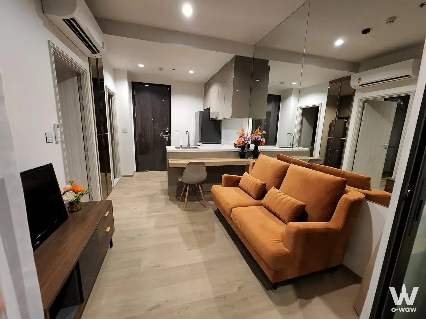 Burnt-orange sofa in open-plan living area of 1-bed condo for rent at Quinn Sukhumvit 101