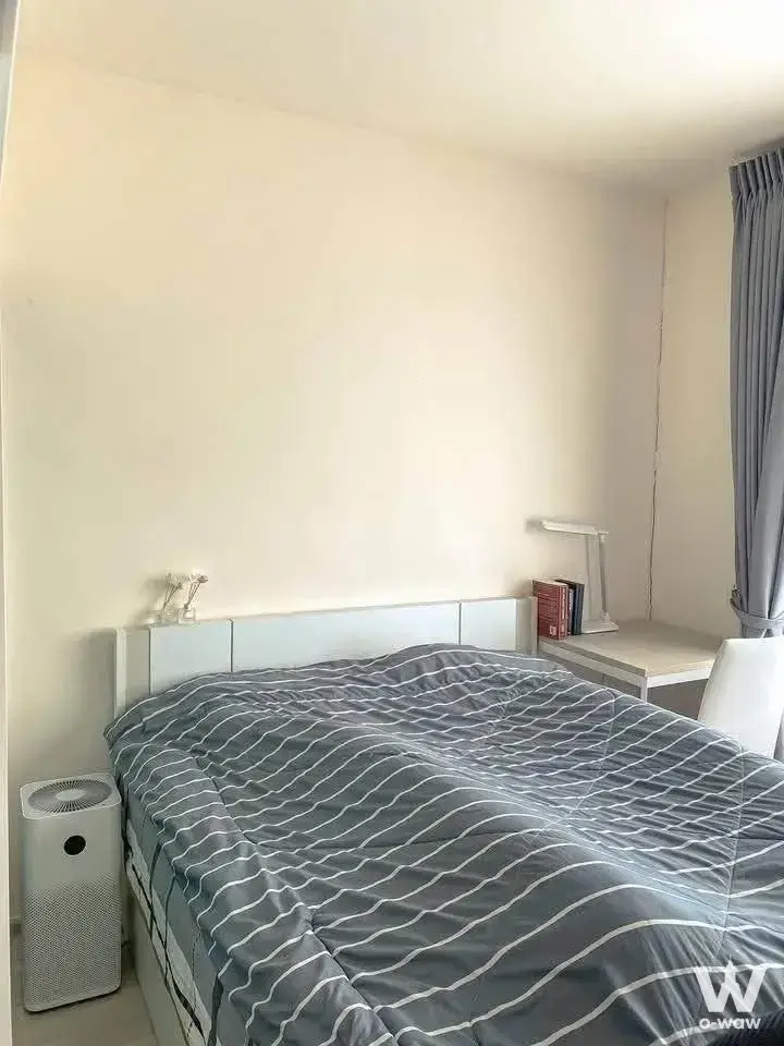 Minimalist bedroom in Aspire Ratchayothin with white queen bed and grey duvet near an air purifier