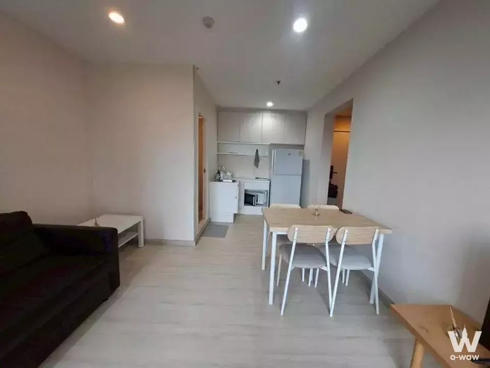 Open-plan studio at Plum Condo Central Station Phase 1 with light wood floors, white kitchen, and modern dining area