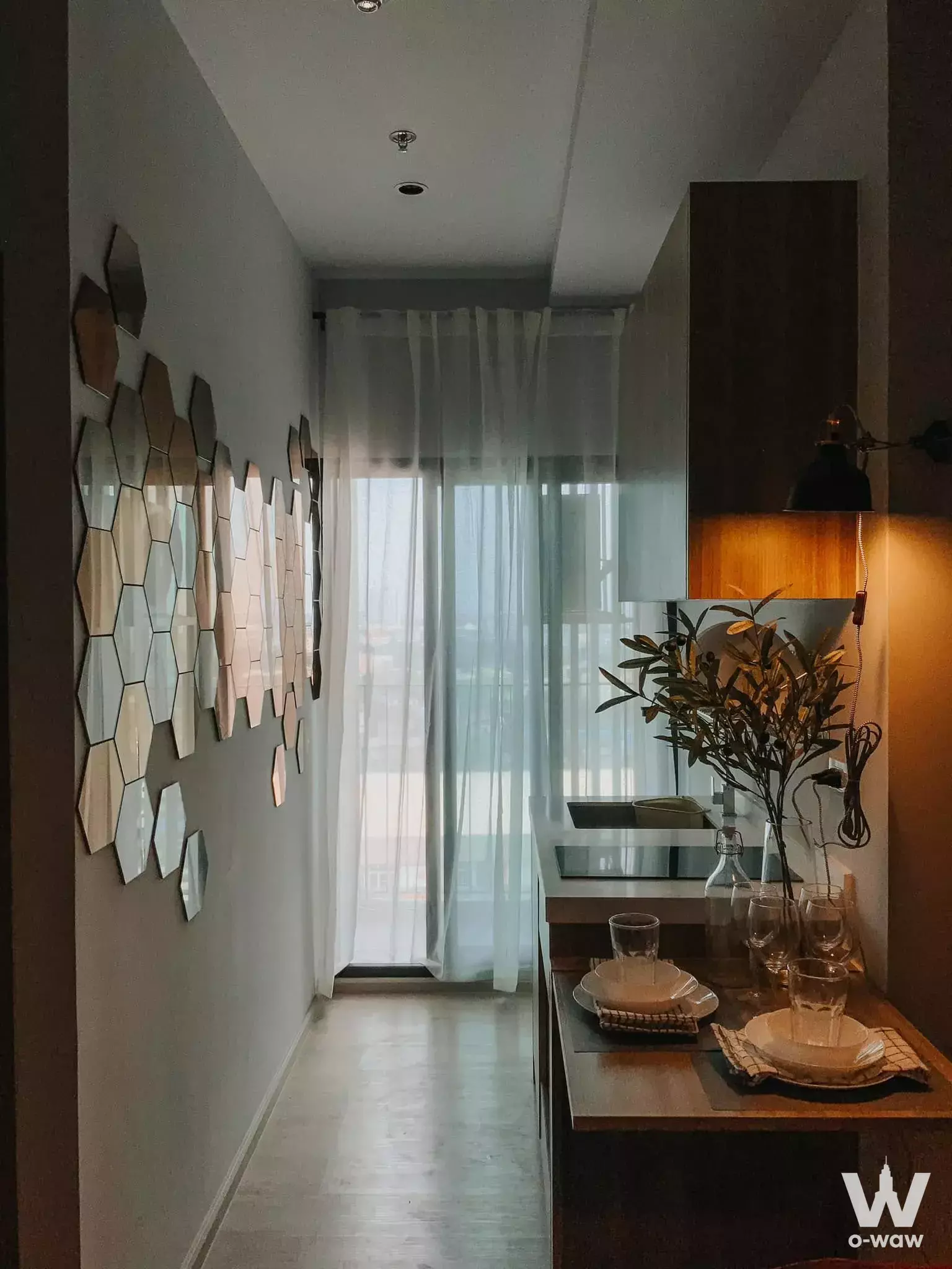 Modern kitchen dining nook in 1-bed Altitude Unicorn-Tha Phra condo with hexagonal mirrors and dark wood island