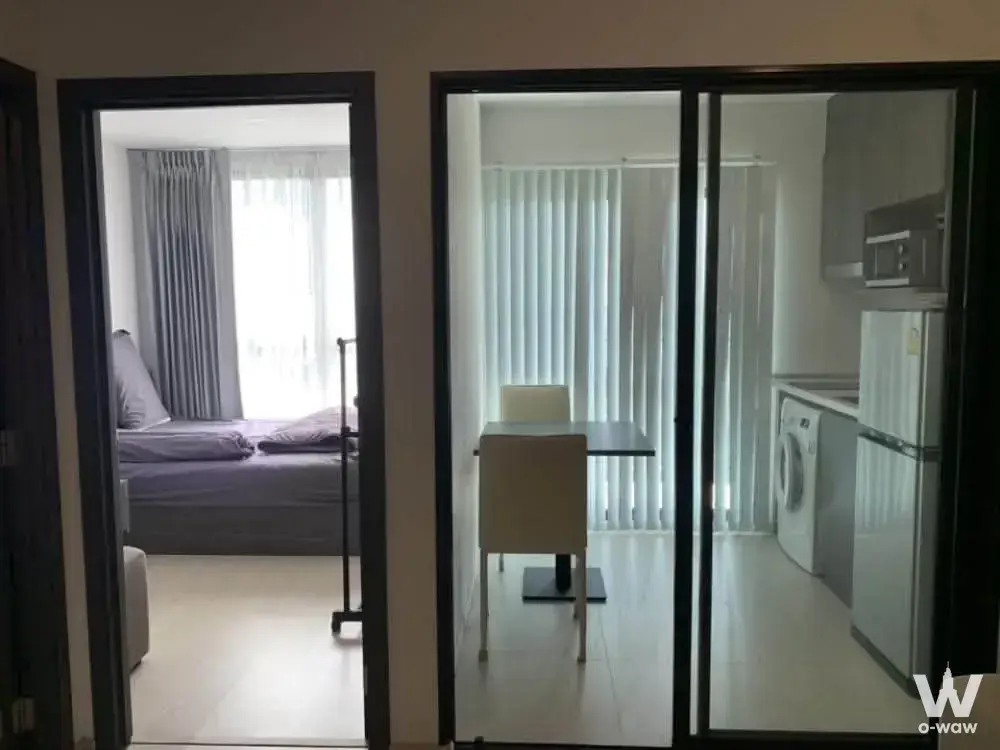 1-bed condo for rent in ELIO DEL NEST featuring grey kitchen cabinetry and a double bed with sheer curtains