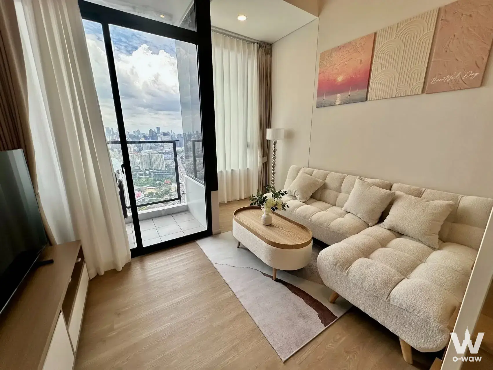 The living room in a 1-bed condo for rent in Siamese Residence, Landmark@MRTA Station, has an L-shaped sofa and city skyline