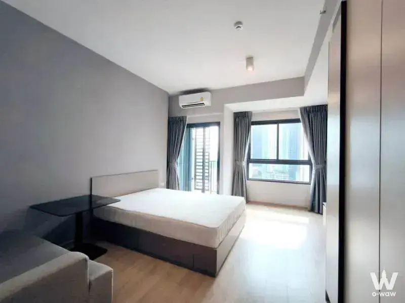 Bright bedroom in 1-bed IDEO Rama 9 condo with wood floors, large windows, and modern built-in storage