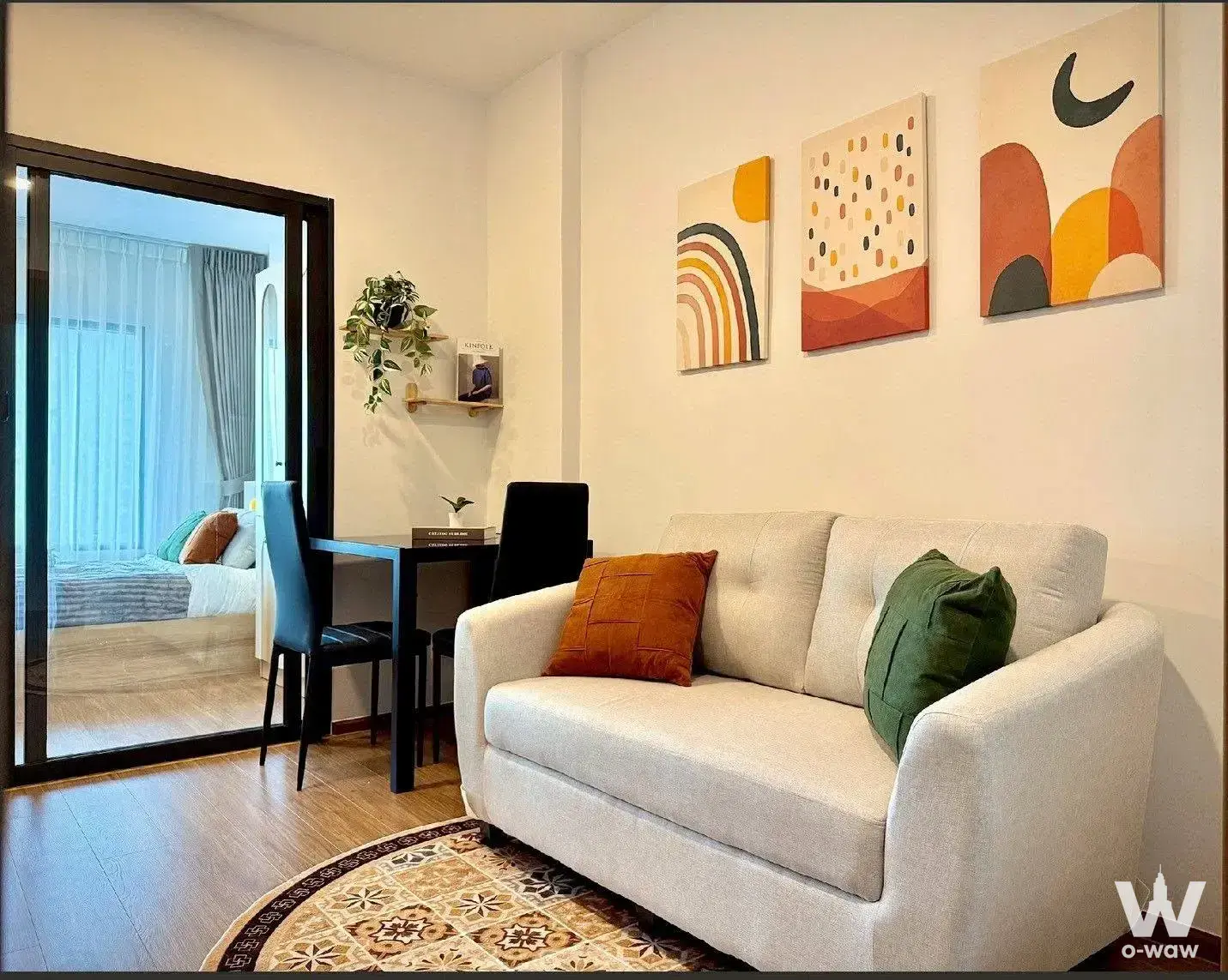 Furnished living room in 1-bed condo for rent at The Livin Ramkhamhaeng with beige sofa and abstract art