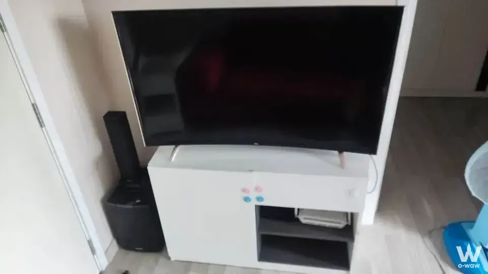 The living room of a 1-bed condo for sale at The Privacy Ladprao - Sena has a black TV and white media cabinet