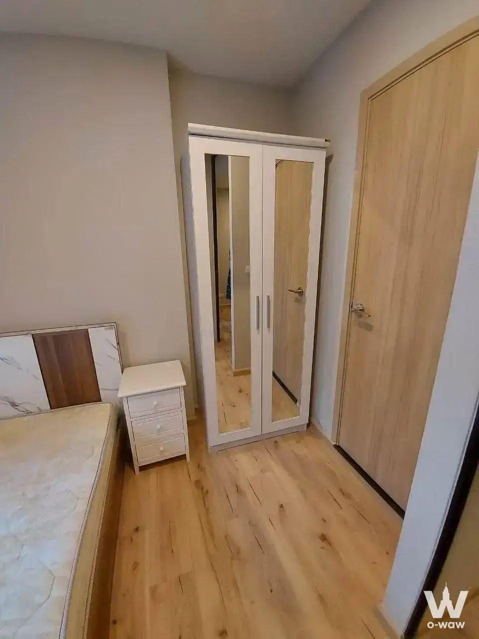 Modern bedroom in 1-bed Brix Charan 64 condo with oak floors, mirrored wardrobe and faux-marble headboard