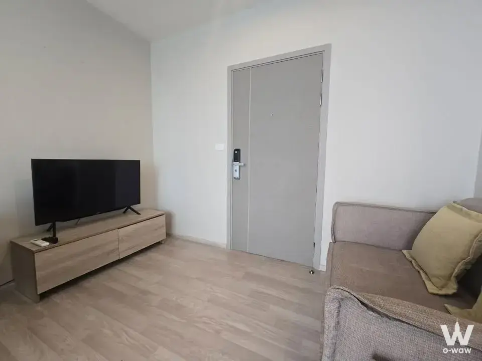Living room with grey sofa and smart-lock entry door in this modern Ideo Mobi Sukhumvit Eastpoint 1-bed rental