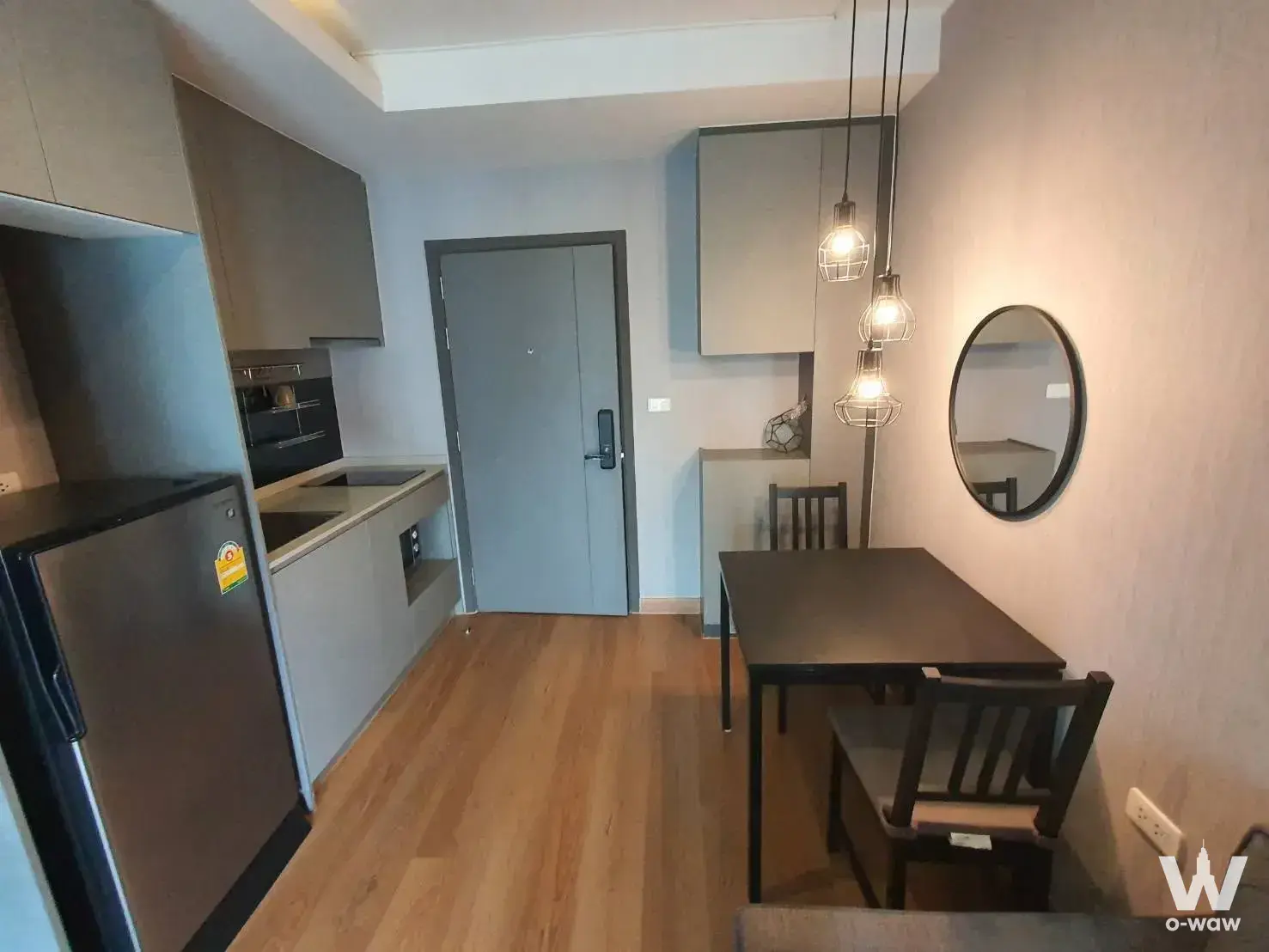 Modern 1-bed condo for sale in Ideo Sukhumvit 93 with grey kitchen cabinets and a dining area under Edison pendant lights