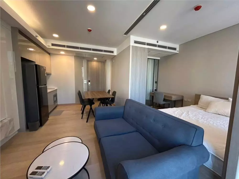 Furnished 1-bed condo for rent in Siamese Exclusive Queens with blue sofa, queen bed, and modern kitchenette