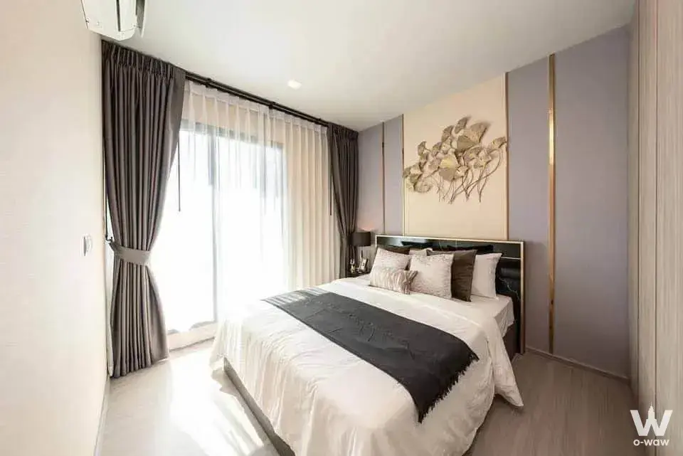 Modern bedroom with queen bed against lavender-grey accent wall with gold trim and sheer curtains over sliding glass doors